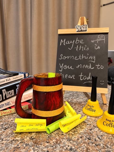 Chalkboard reading 'Maybe this is something you need to hear today' beside a mug and coffee bells