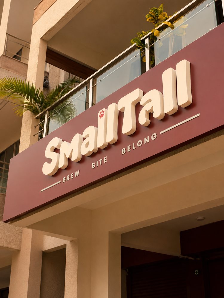 The Small Tall signboard with the paw-print logo and 'Brew Bite Belong' above the café entrance